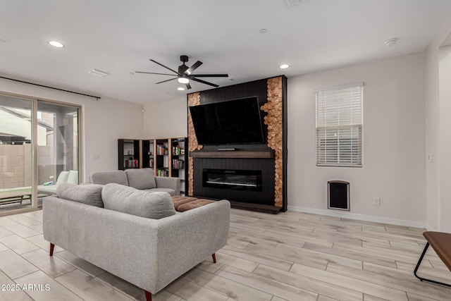 living room with a fireplace, light hardwood / wood-style floors, and ceiling fan