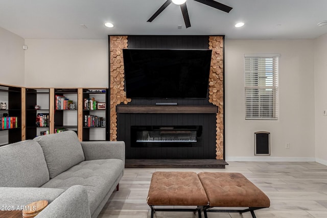 living room with a fireplace, light hardwood / wood-style floors, and ceiling fan