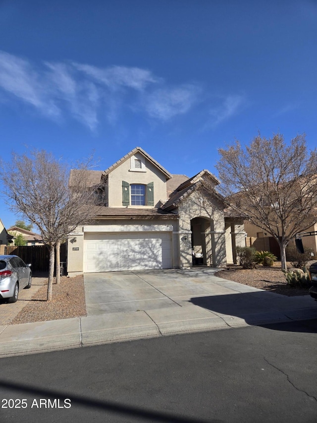 view of front of home with concrete driveway, a tiled roof, an attached garage, fence, and stucco siding