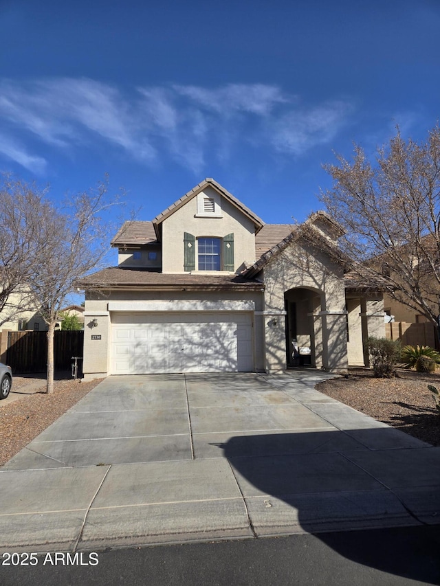 view of front of property with driveway, an attached garage, fence, and stucco siding