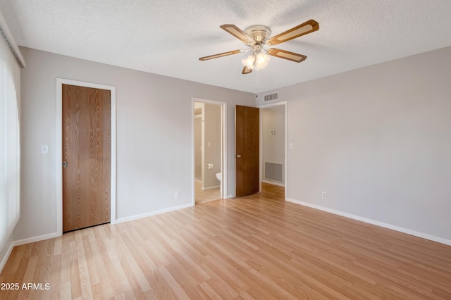 unfurnished bedroom with a textured ceiling, light wood-type flooring, and visible vents