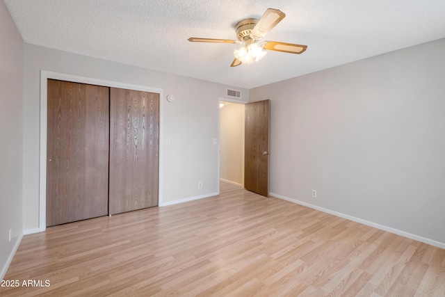 unfurnished bedroom featuring a textured ceiling, a closet, wood finished floors, and baseboards