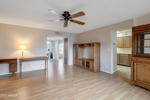 unfurnished living room with visible vents, baseboards, a ceiling fan, light wood-style flooring, and a textured ceiling