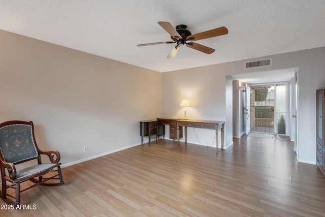 unfurnished room with baseboards, a textured ceiling, visible vents, and wood finished floors