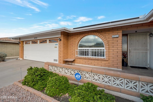 view of front of home with concrete driveway, brick siding, and an attached garage