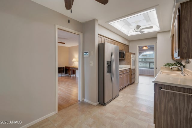 kitchen featuring a sink, a ceiling fan, baseboards, light countertops, and appliances with stainless steel finishes