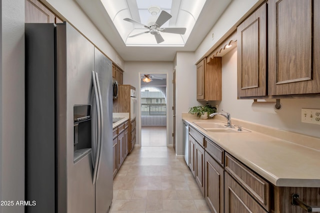 kitchen featuring a sink, a ceiling fan, light countertops, appliances with stainless steel finishes, and brown cabinets