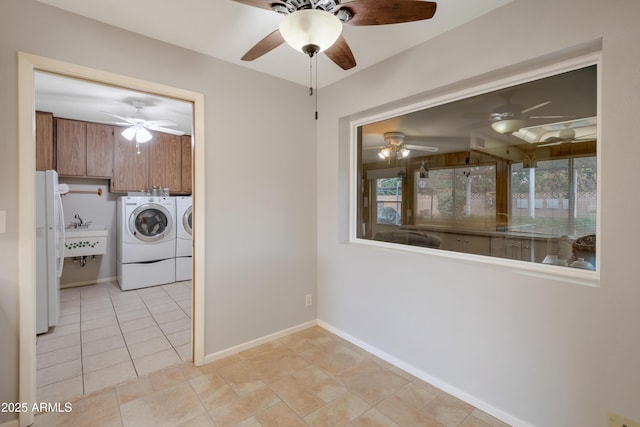 clothes washing area featuring light tile patterned floors, laundry area, a sink, baseboards, and washer and clothes dryer