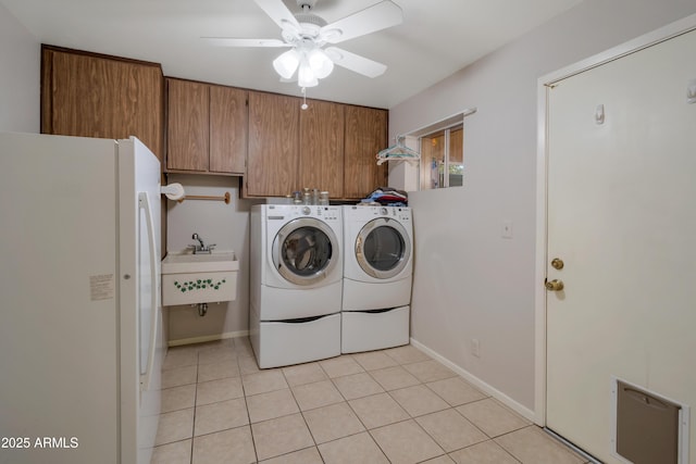 washroom featuring ceiling fan, light tile patterned flooring, separate washer and dryer, a sink, and cabinet space