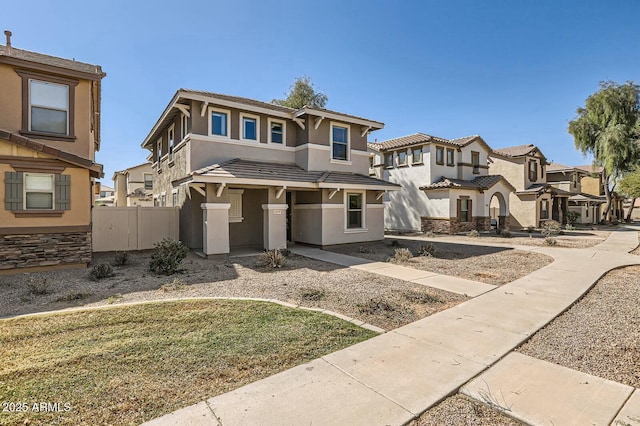 view of front of house with a residential view, fence, a tiled roof, and stucco siding