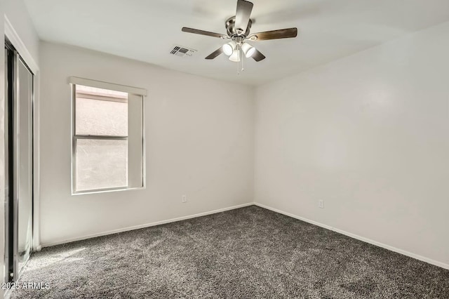 empty room with carpet floors, baseboards, visible vents, and ceiling fan