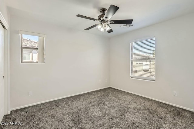 carpeted spare room featuring baseboards, visible vents, and a ceiling fan