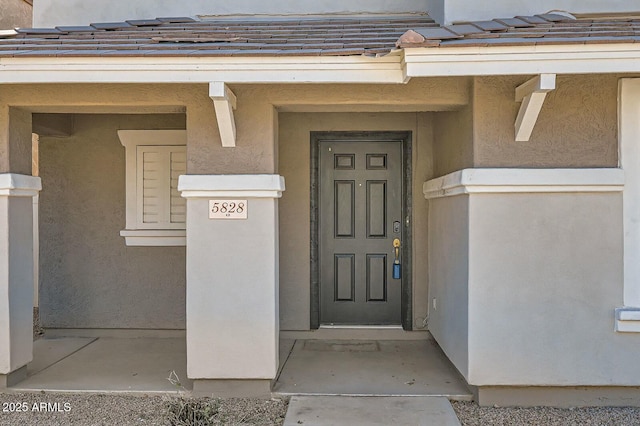 property entrance with a tiled roof and stucco siding