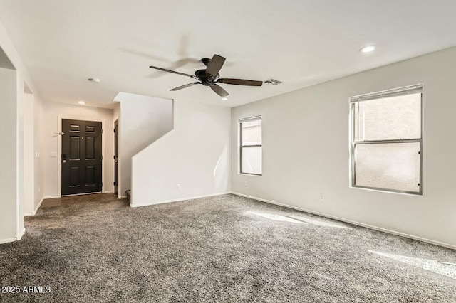 unfurnished room with carpet, a healthy amount of sunlight, visible vents, and baseboards