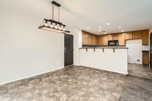 kitchen featuring baseboards, dark countertops, a kitchen breakfast bar, black microwave, and recessed lighting