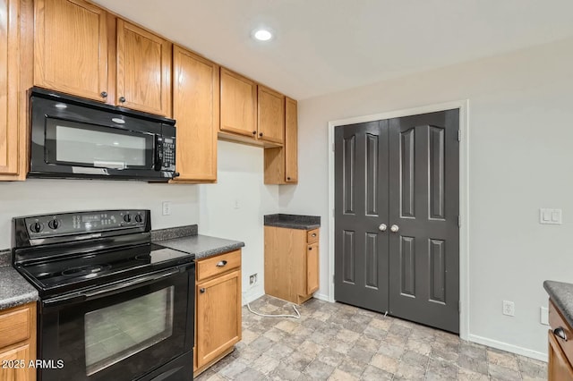 kitchen featuring dark countertops, recessed lighting, stone finish floor, black appliances, and baseboards