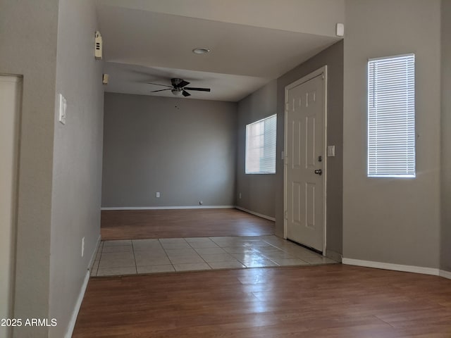 foyer entrance with wood finished floors, a ceiling fan, and baseboards