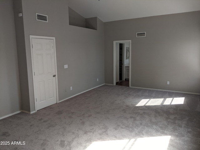 spare room with carpet floors, visible vents, high vaulted ceiling, and baseboards