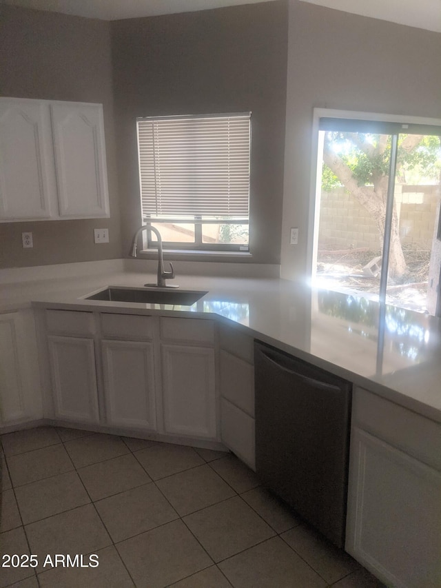 kitchen featuring light tile patterned floors, a sink, white cabinetry, light countertops, and stainless steel dishwasher