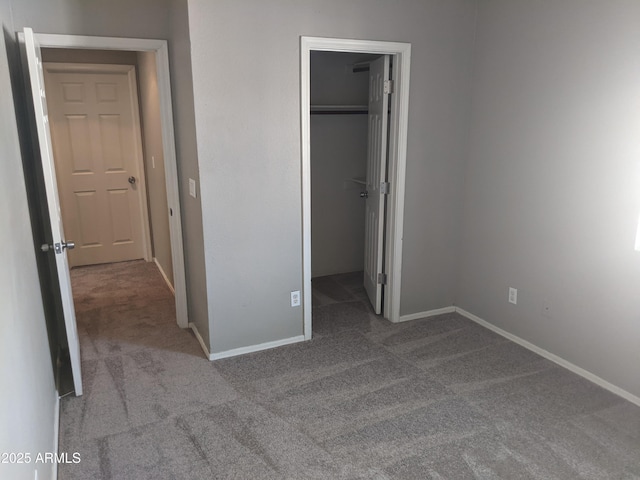 unfurnished bedroom featuring carpet floors, baseboards, and a walk in closet