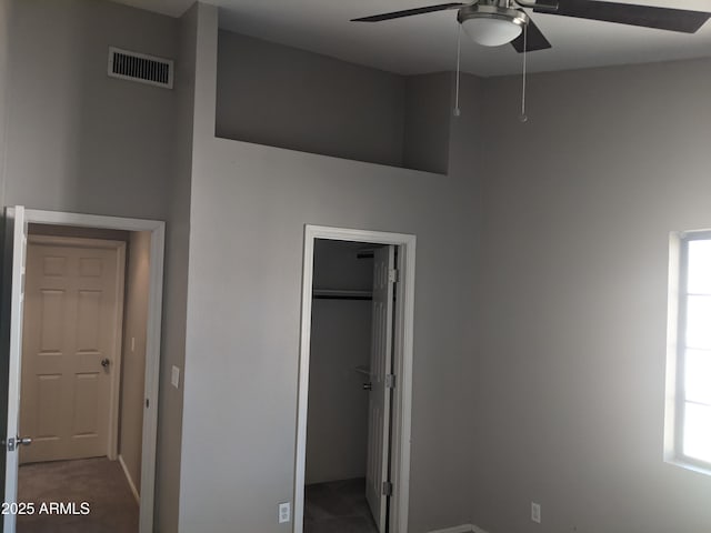 unfurnished bedroom with multiple windows, a closet, visible vents, and a walk in closet