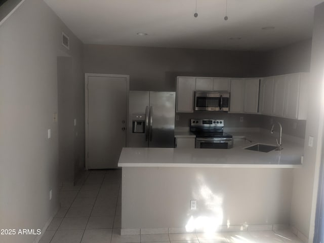 kitchen featuring a peninsula, a sink, visible vents, light countertops, and appliances with stainless steel finishes