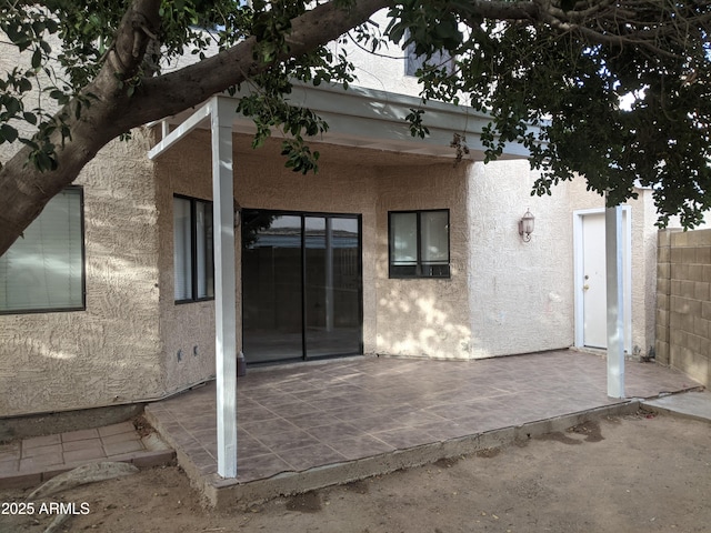 back of house featuring a patio area, fence, and stucco siding