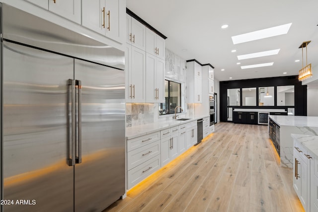 kitchen with white cabinetry, stainless steel appliances, sink, and pendant lighting