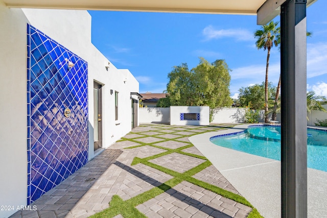 view of swimming pool with exterior fireplace and a patio area