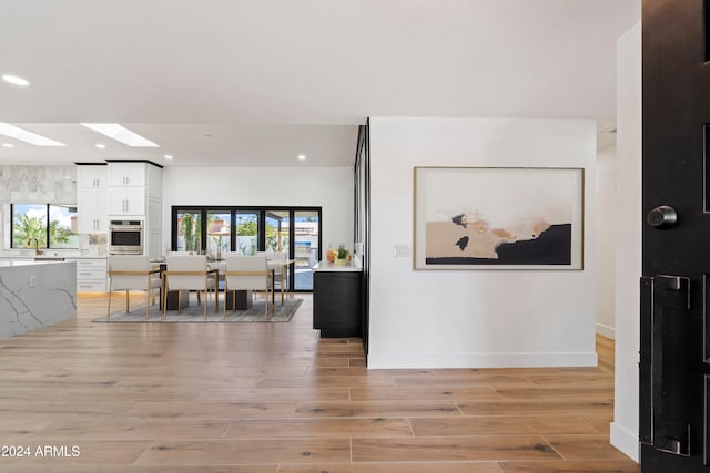 interior space with a skylight and light hardwood / wood-style floors