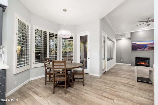 dining room with ceiling fan, light hardwood / wood-style floors, and a fireplace