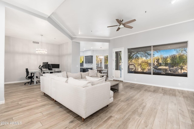 living room featuring ceiling fan with notable chandelier and light wood-type flooring