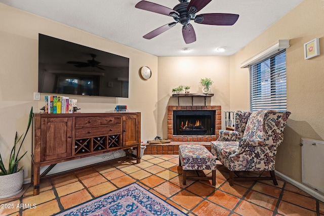 living area featuring ceiling fan and a fireplace