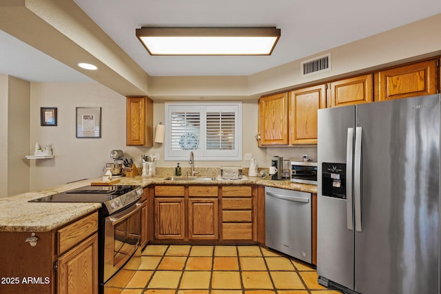 kitchen with stainless steel appliances, kitchen peninsula, sink, and light stone countertops