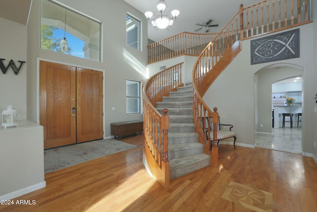 entrance foyer featuring a high ceiling, light wood-type flooring, and ceiling fan with notable chandelier