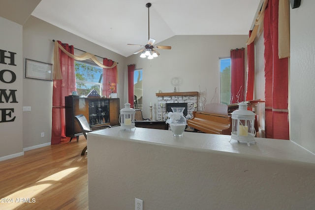 kitchen with lofted ceiling, hardwood / wood-style flooring, a fireplace, and ceiling fan