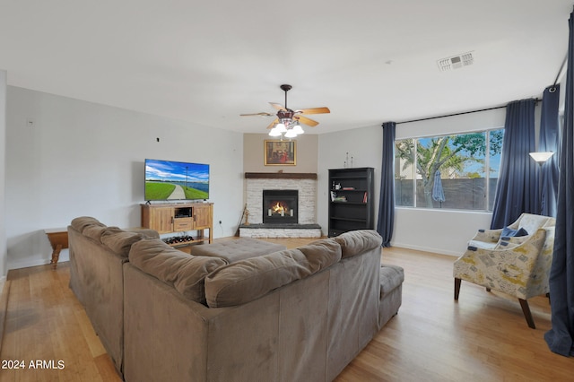 living room with light hardwood / wood-style flooring, a fireplace, and ceiling fan