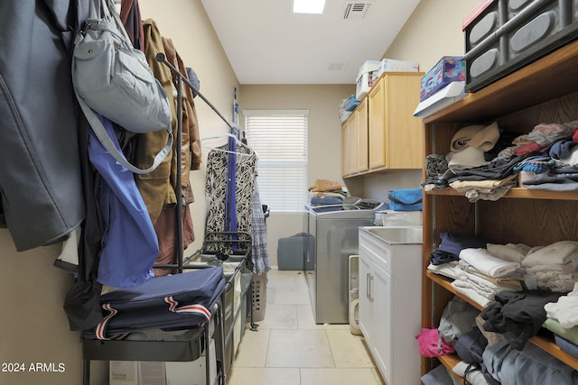 washroom with cabinets, washing machine and dryer, and light tile patterned floors