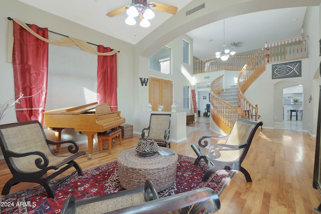 living room featuring light hardwood / wood-style floors, high vaulted ceiling, and ceiling fan with notable chandelier