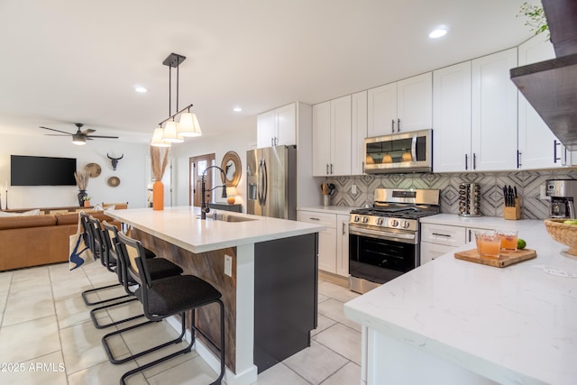 6907 E Palm Ln, Scottsdale, AZ 85257 - kitchen with appliances with stainless steel finishes, decorative backsplash, open floor plan, ceiling fan, and light tile patterned floors