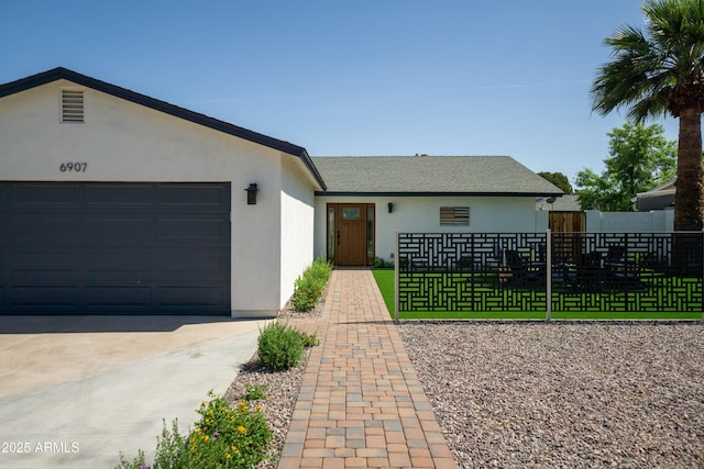 6907 E Palm Ln, Scottsdale, AZ 85257 - view of front facade with stucco siding, an attached garage, and driveway