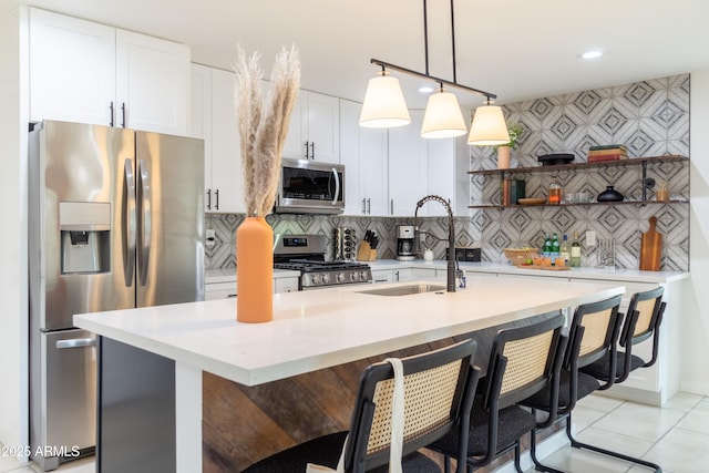 6907 E Palm Ln, Scottsdale, AZ 85257 - kitchen featuring appliances with stainless steel finishes, open shelves, a breakfast bar area, a kitchen island with sink, and white cabinets