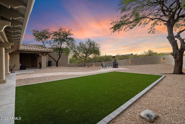 yard at dusk featuring a patio