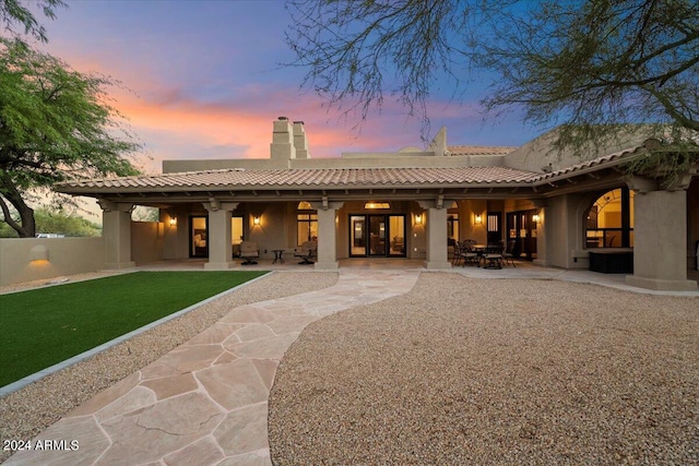 back house at dusk featuring a patio area