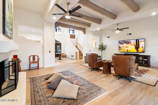 living room featuring ceiling fan, light hardwood / wood-style flooring, and beam ceiling