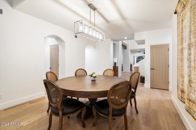 dining area with an inviting chandelier and light hardwood / wood-style flooring