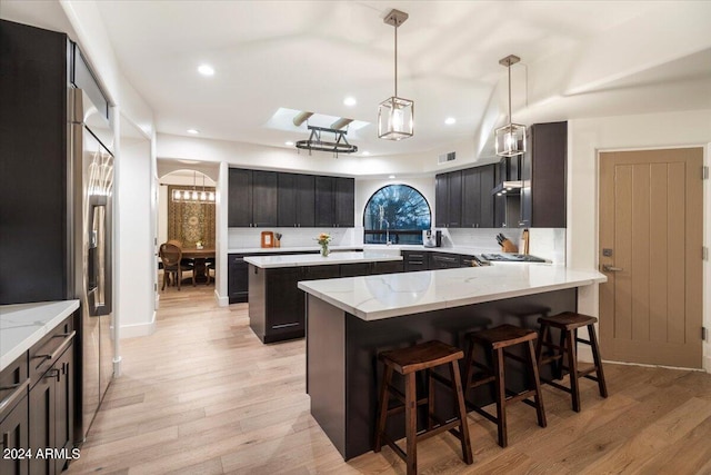 kitchen featuring kitchen peninsula, decorative light fixtures, light hardwood / wood-style floors, decorative backsplash, and a kitchen island