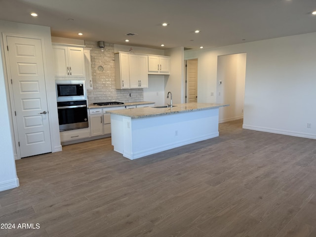 kitchen featuring tasteful backsplash, stainless steel appliances, light hardwood / wood-style flooring, white cabinets, and an island with sink