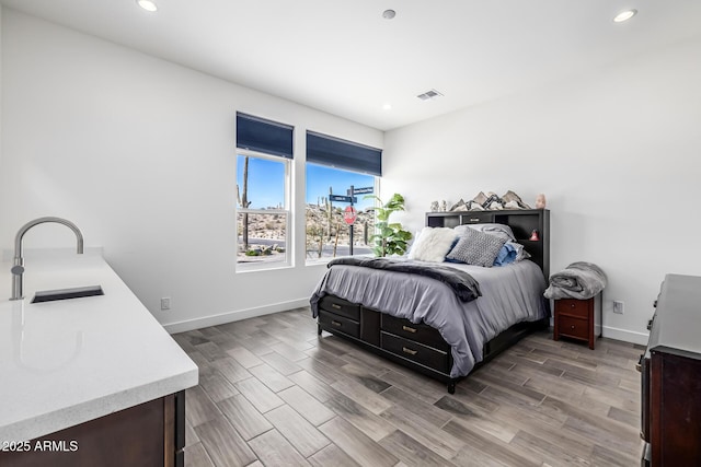 bedroom with wood finish floors, a sink, visible vents, and recessed lighting