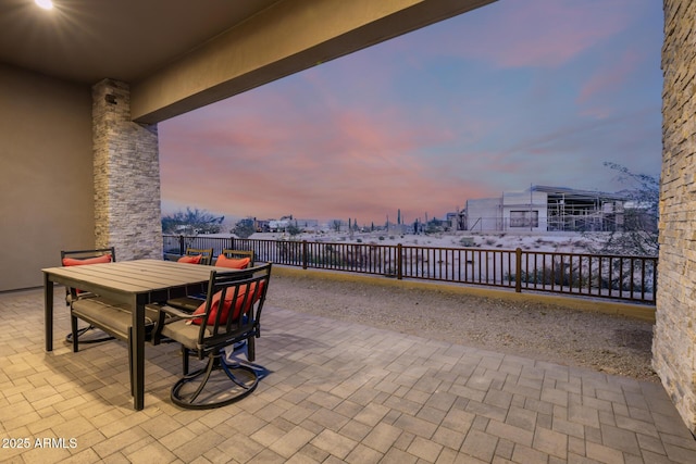 patio terrace at dusk with outdoor dining space and a fenced backyard